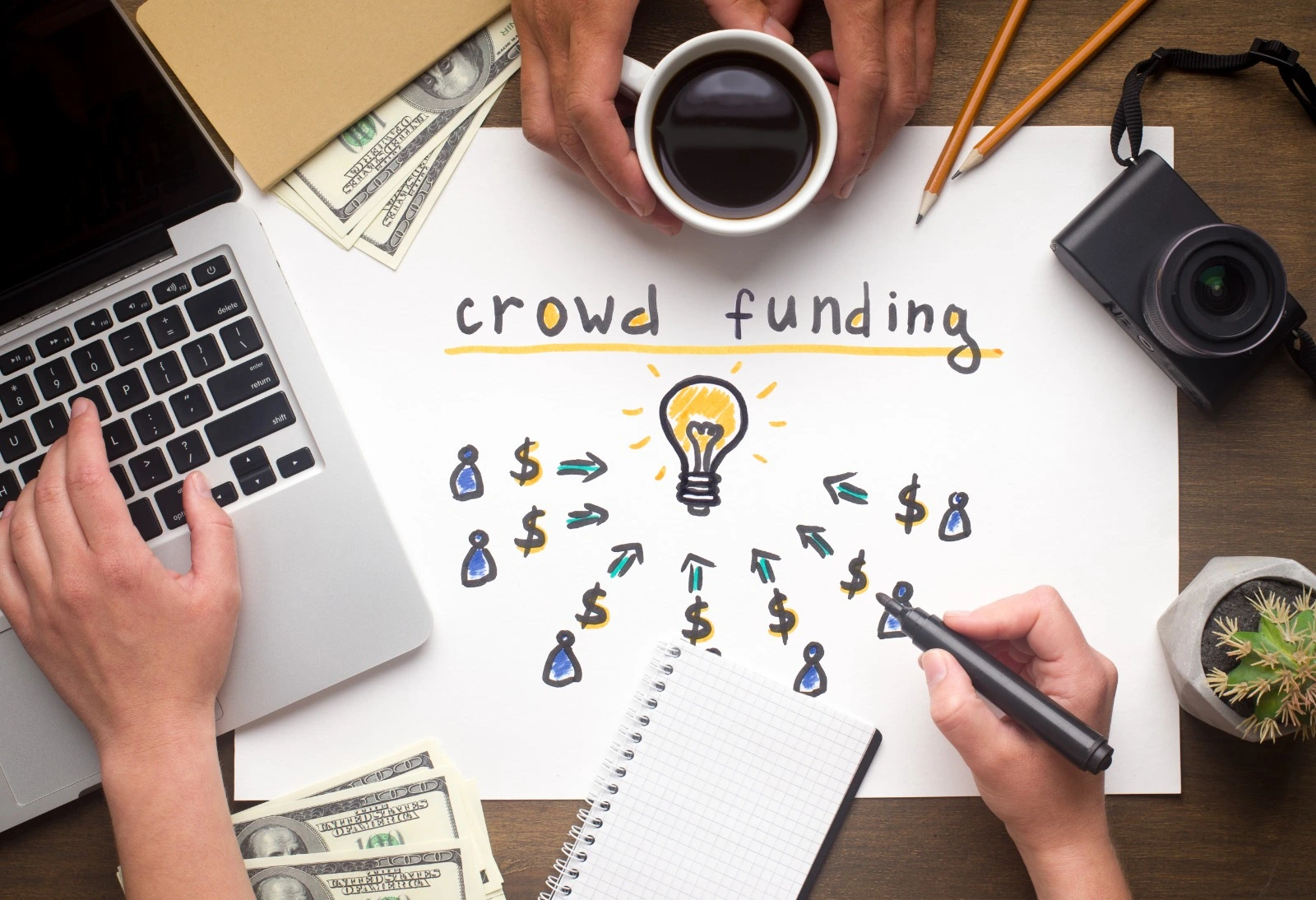 mano dibujando sobre una hoja mostrando la palabra "crowdfunding"