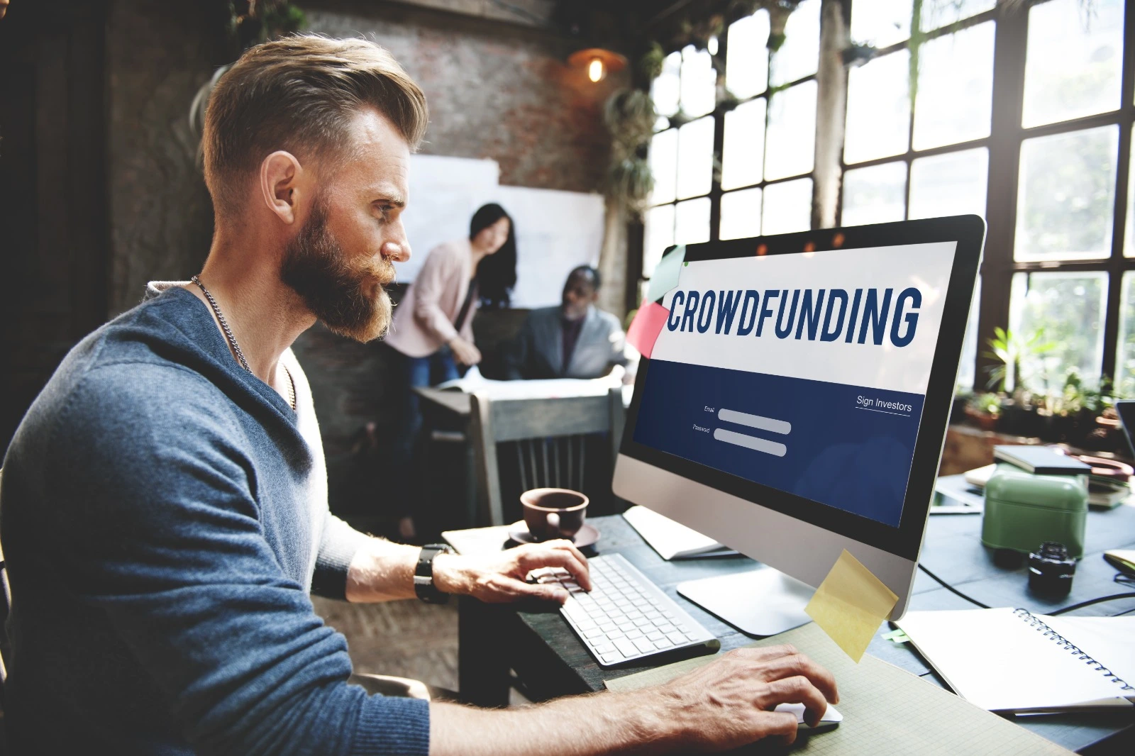hombre al frente de una pantalla mostrando la palabra "crowdfunding"