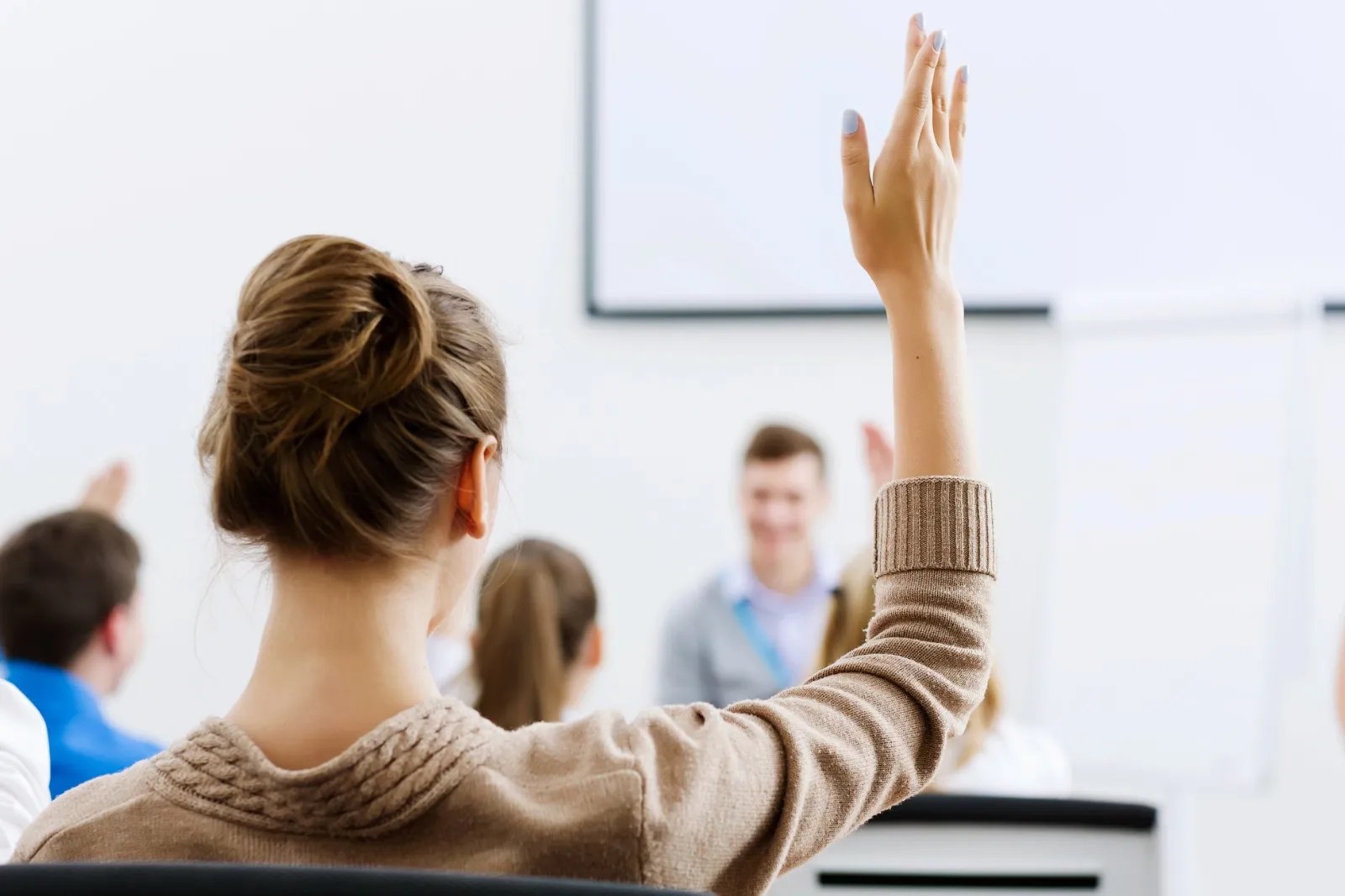 salón de clases con mujer levantando su mano en el aire