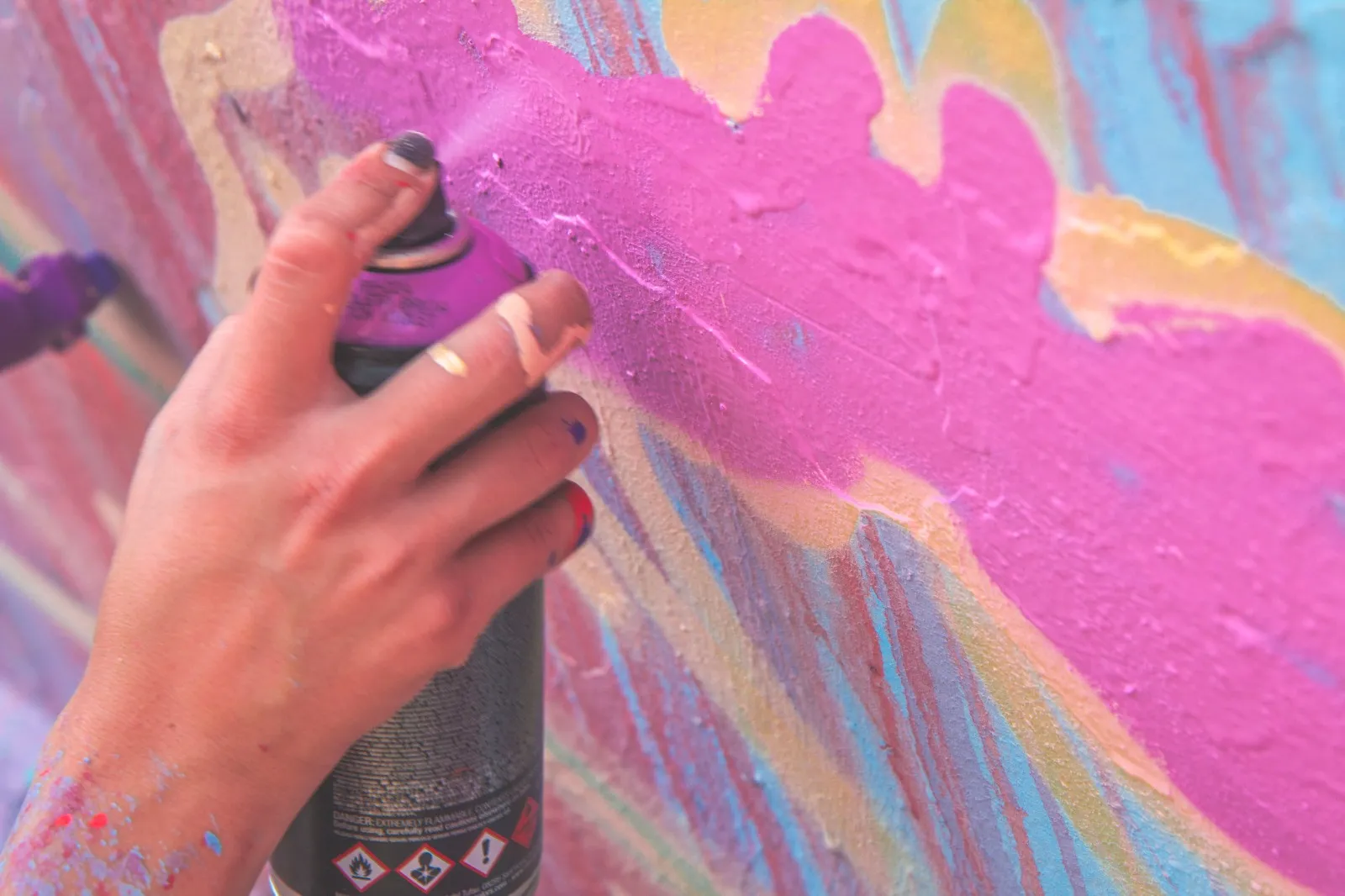 mano pintando una pared con pintura de aerosol rosa