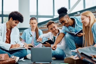 Feliz estudiante de medicina afroamericano y sus amigos cooperando mientras aprenden en e-learning en la sala de conferencias. 