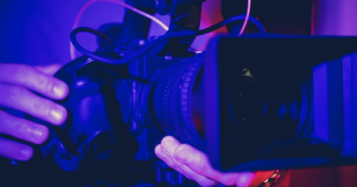 Profesión Cámara de vídeo digital en movimiento en las manos de los operadores dentro de la habitación azul oscuro iluminada. Equipo de producción de TV y cine.